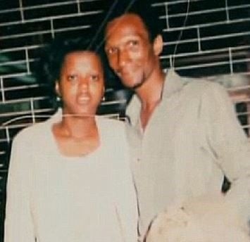 Joe Odom posing with his wife in white shirt.